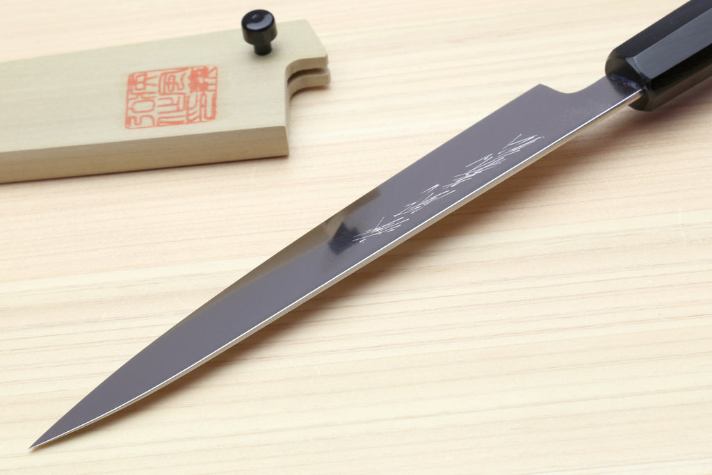 Petty utility knife with stainless blade and dark handle on light wood board