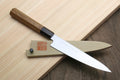 Petty utility knife with stainless blade, wood handle, and saya cover near board