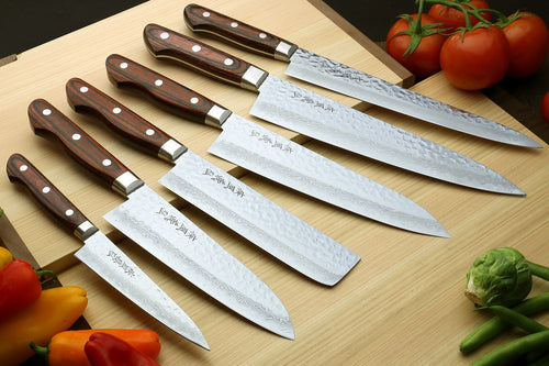 Damascus kitchen knives arranged on wooden board with dark wood handles