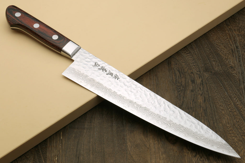 Damascus kitchen knife on wooden surface with dark wood handle