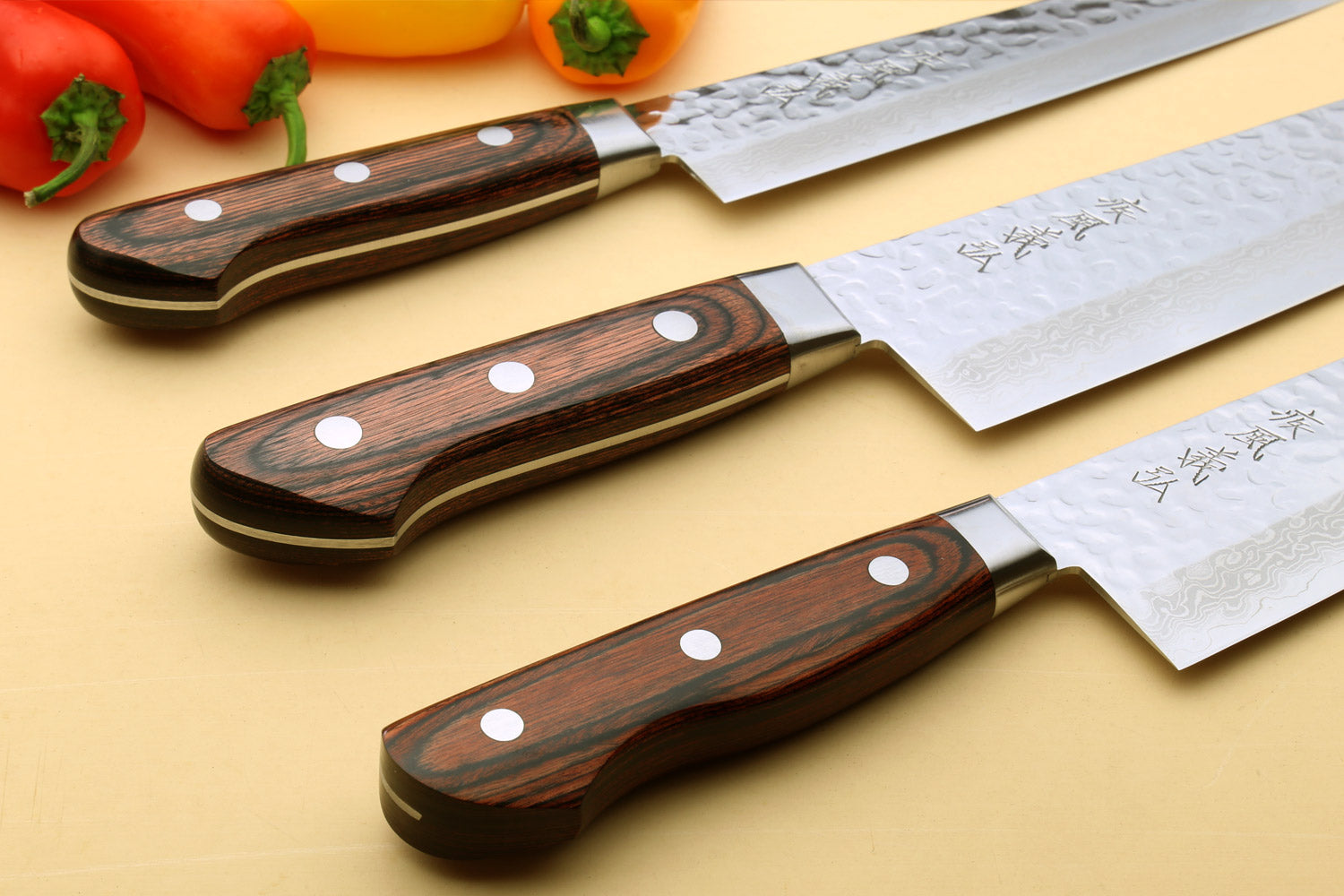 Damascus chef knife set with dark wood handles, three blades shown side by side