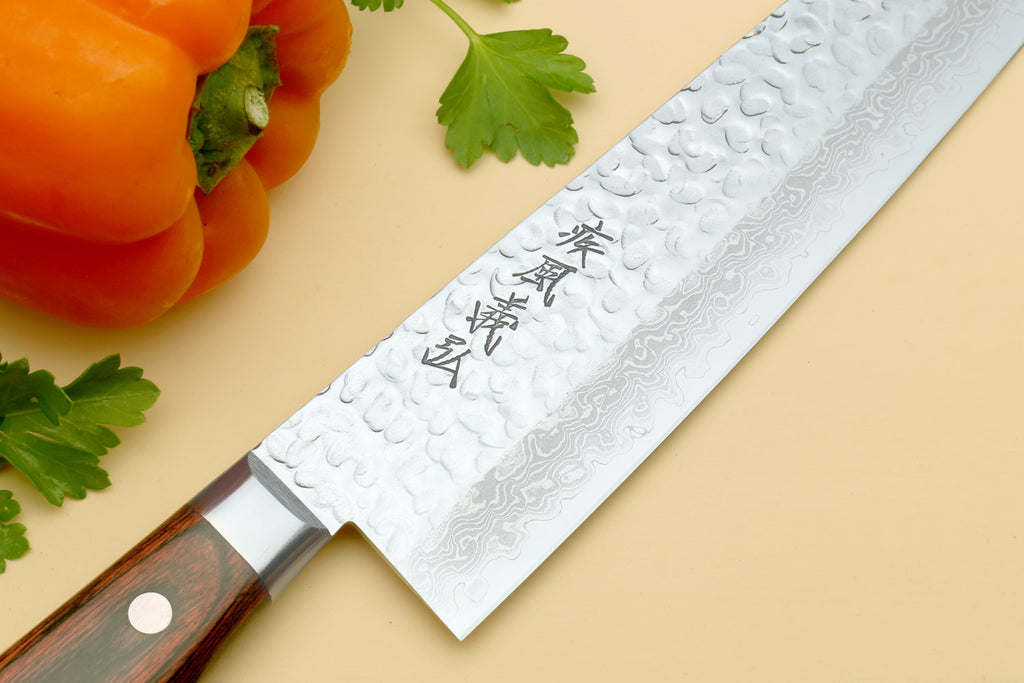 Damascus gyuto chef knife close-up, hammered silver blade with etched characters