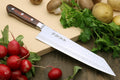 Kiritsuke knife with hammered Damascus blade, dark handle, and metal bolster