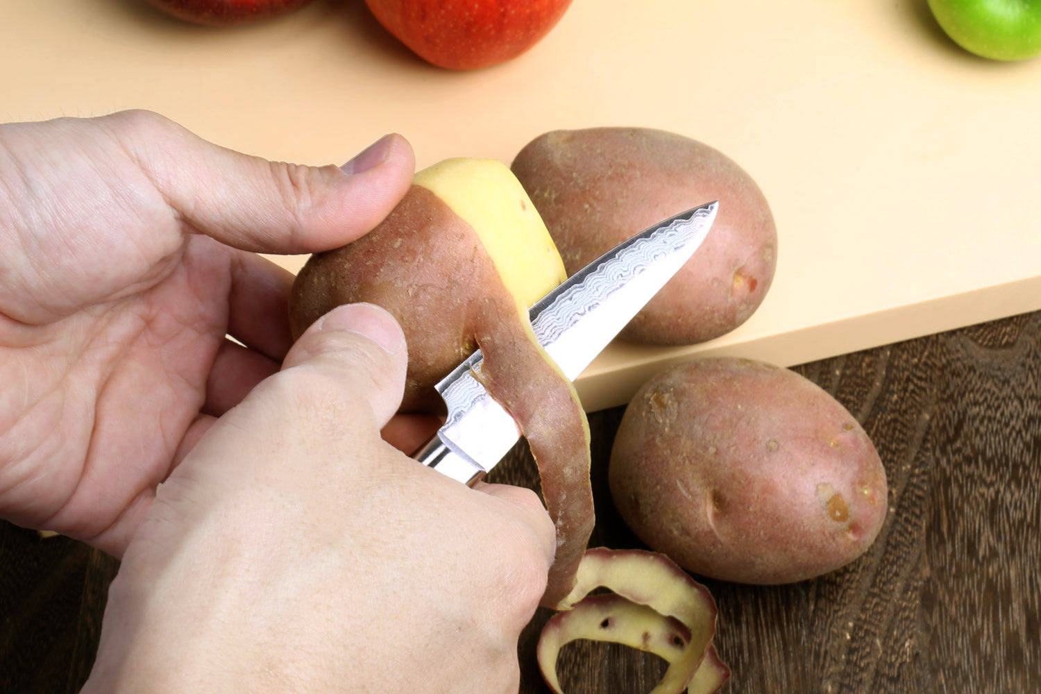 Paring knife with hammered Damascus blade, dark handle, cutting potatoes