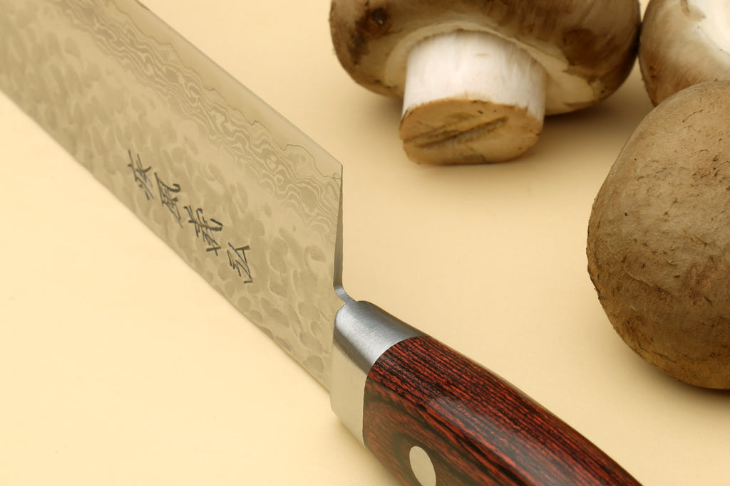 Nakiri vegetable knife angled view with hammered blade, dark wood handle, mushrooms nearby