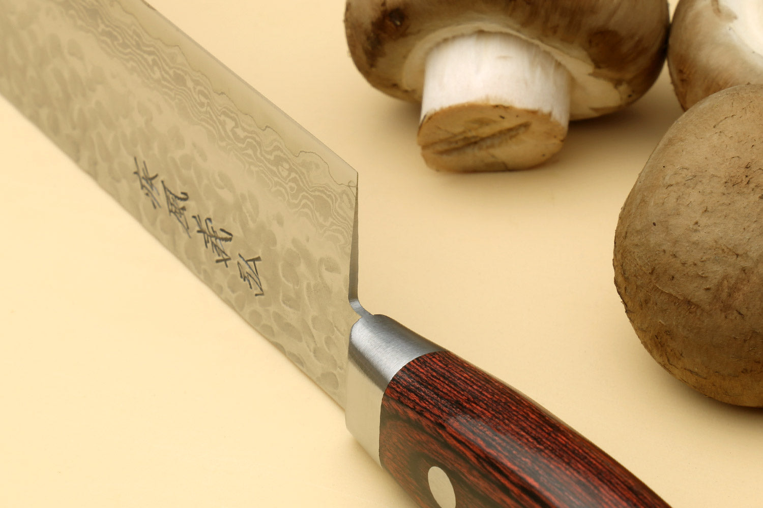 Nakiri vegetable knife angled view with hammered blade, dark wood handle, mushrooms nearby