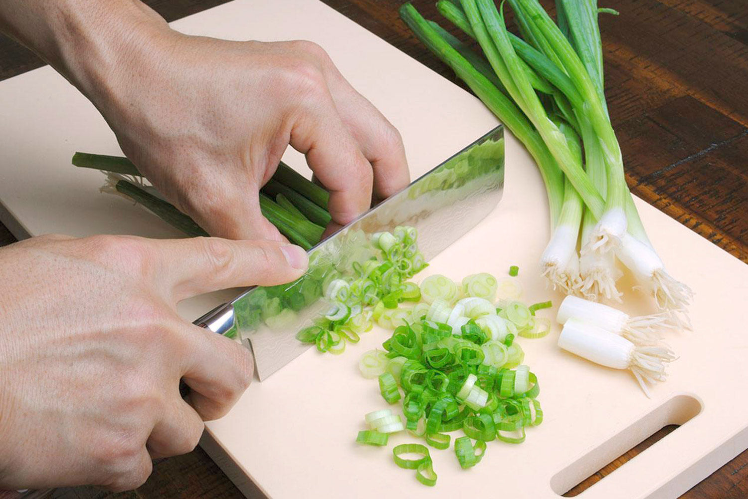 Nakiri vegetable knife chopping green onions; hammered blade and dark wood handle in use