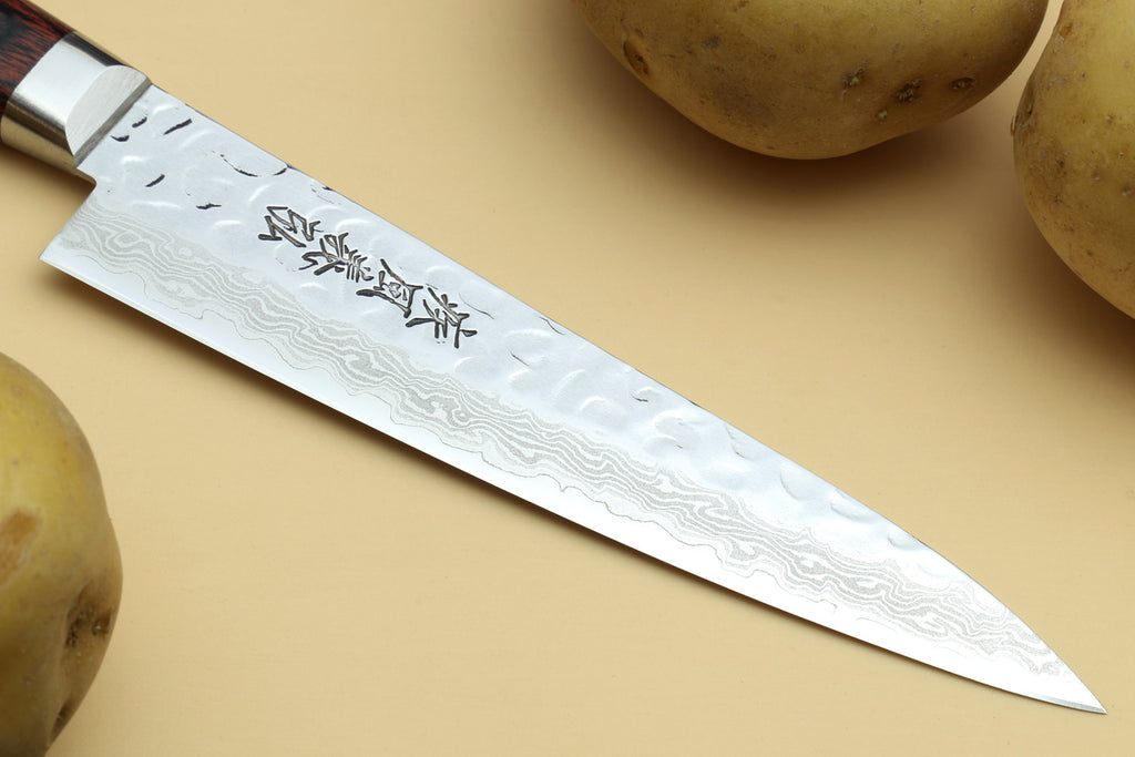 Petty knife blade close-up with etched damascus pattern and stamped characters