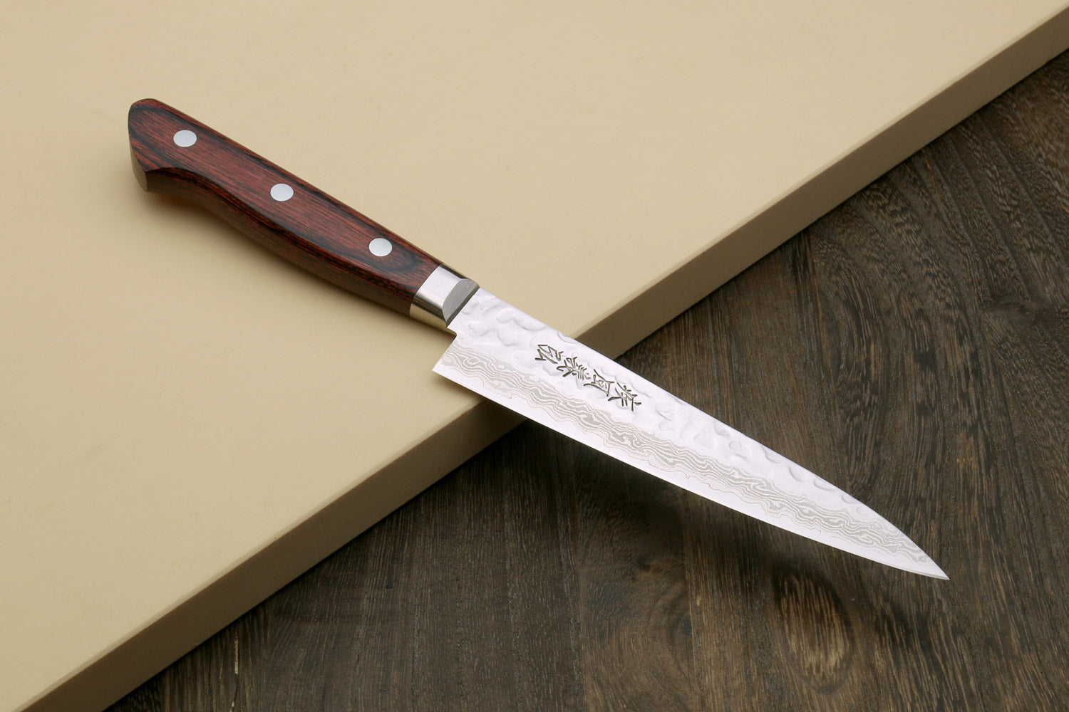 Petty knife with hammered damascus blade and dark red-brown wood handle rivets