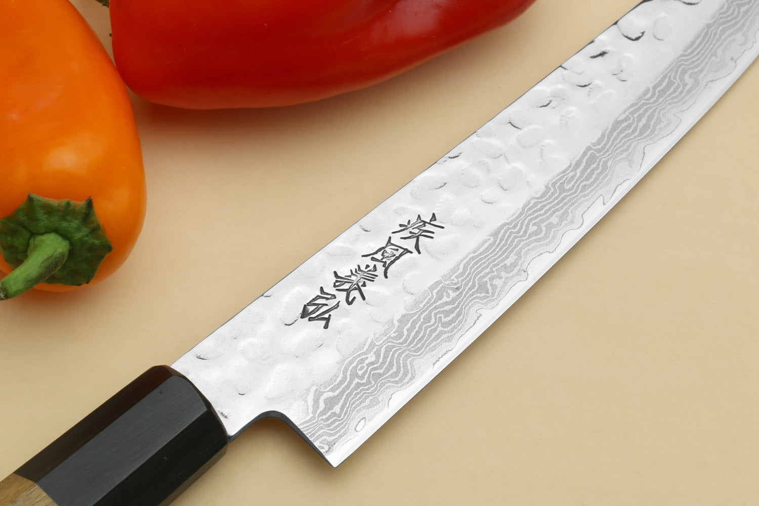 Petty utility chef knife blade close-up with engraved logo and Damascus pattern