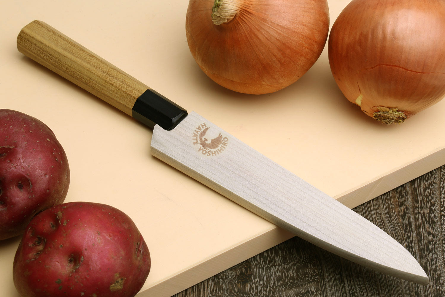 Petty utility chef knife on cutting board with Damascus-pattern blade and wood handle