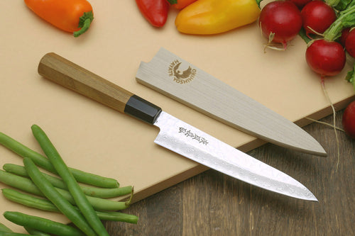 Petty utility chef knife with Damascus blade and light wood handle on cutting board