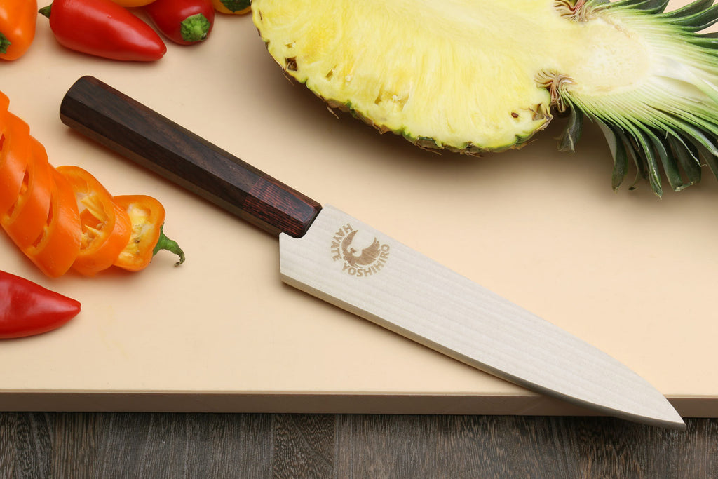 Petty utility knife resting on board, hammered Damascus blade and rosewood handle