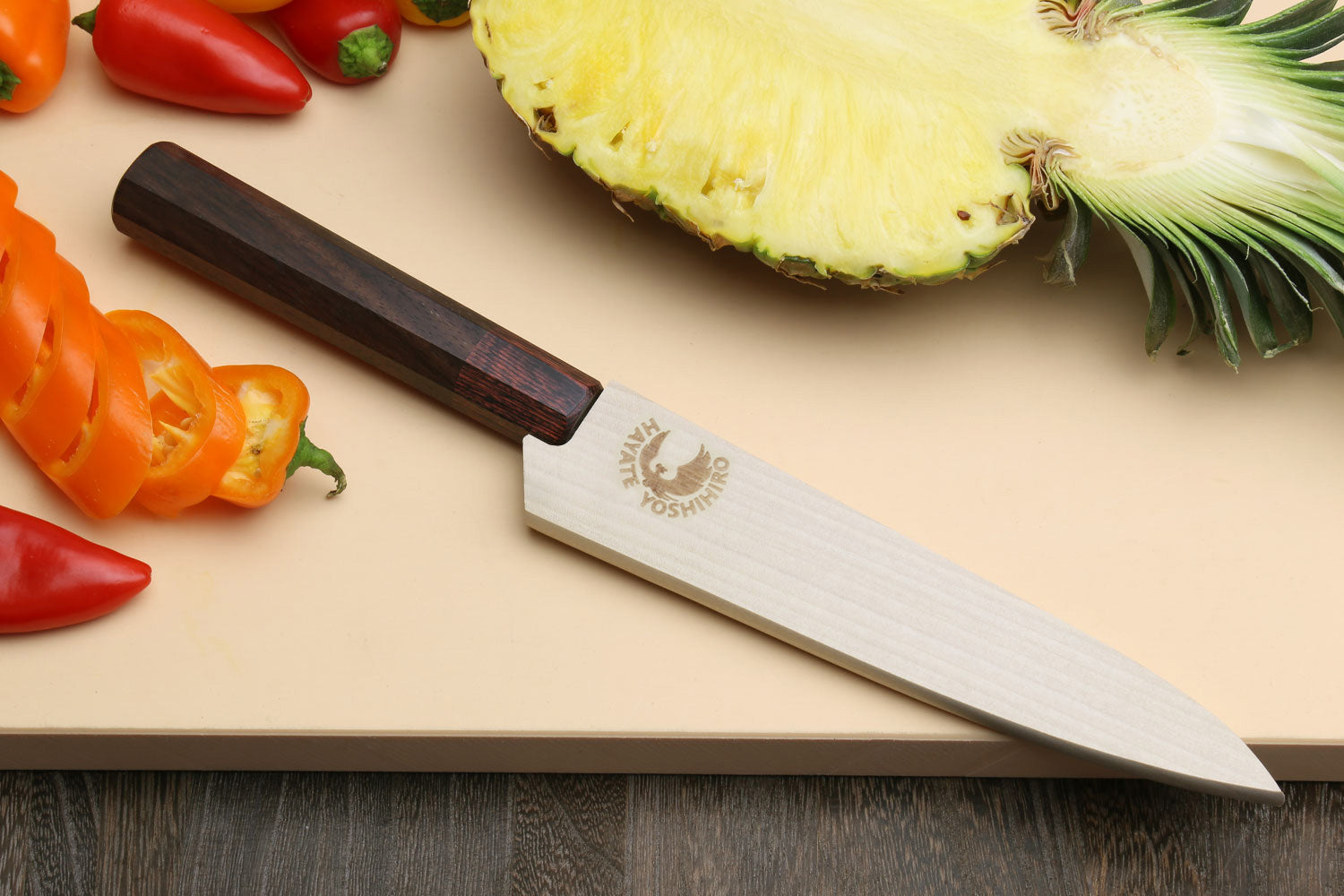 Petty utility knife resting on board, hammered Damascus blade and rosewood handle