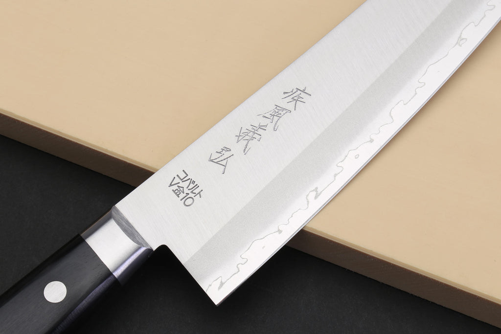 Gyuto chef knife showing etched blade and black handle with rivets.