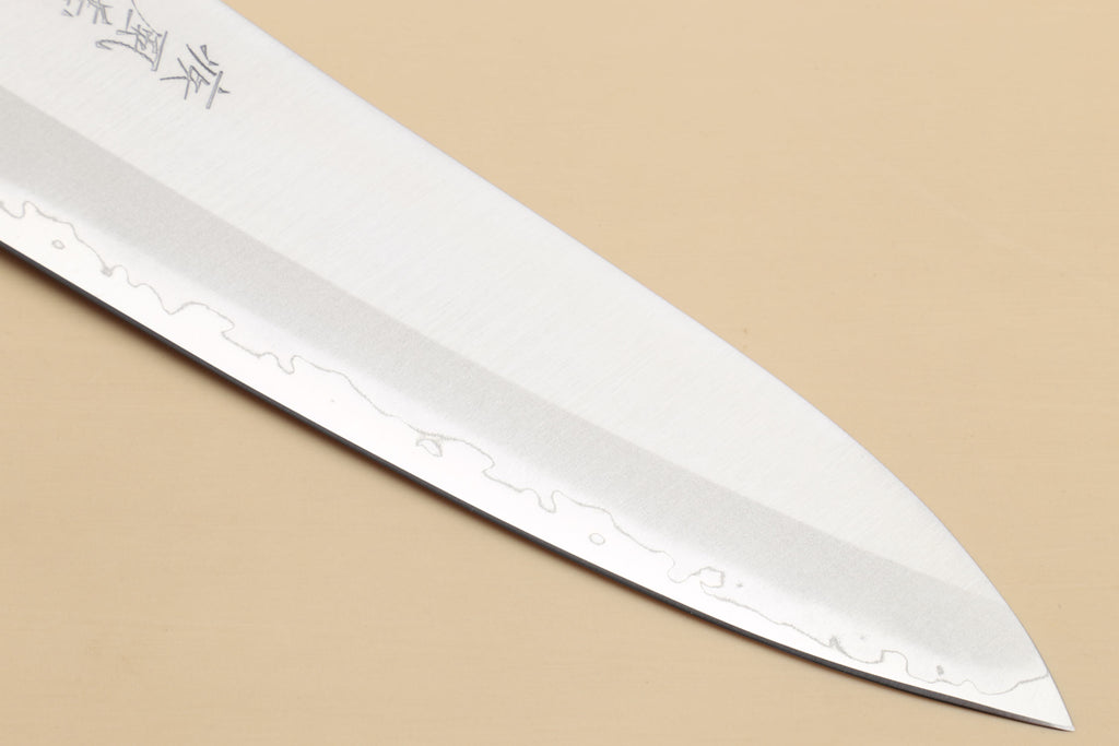 Gyuto chef knife blade tip close-up with etched finish and sharp point.