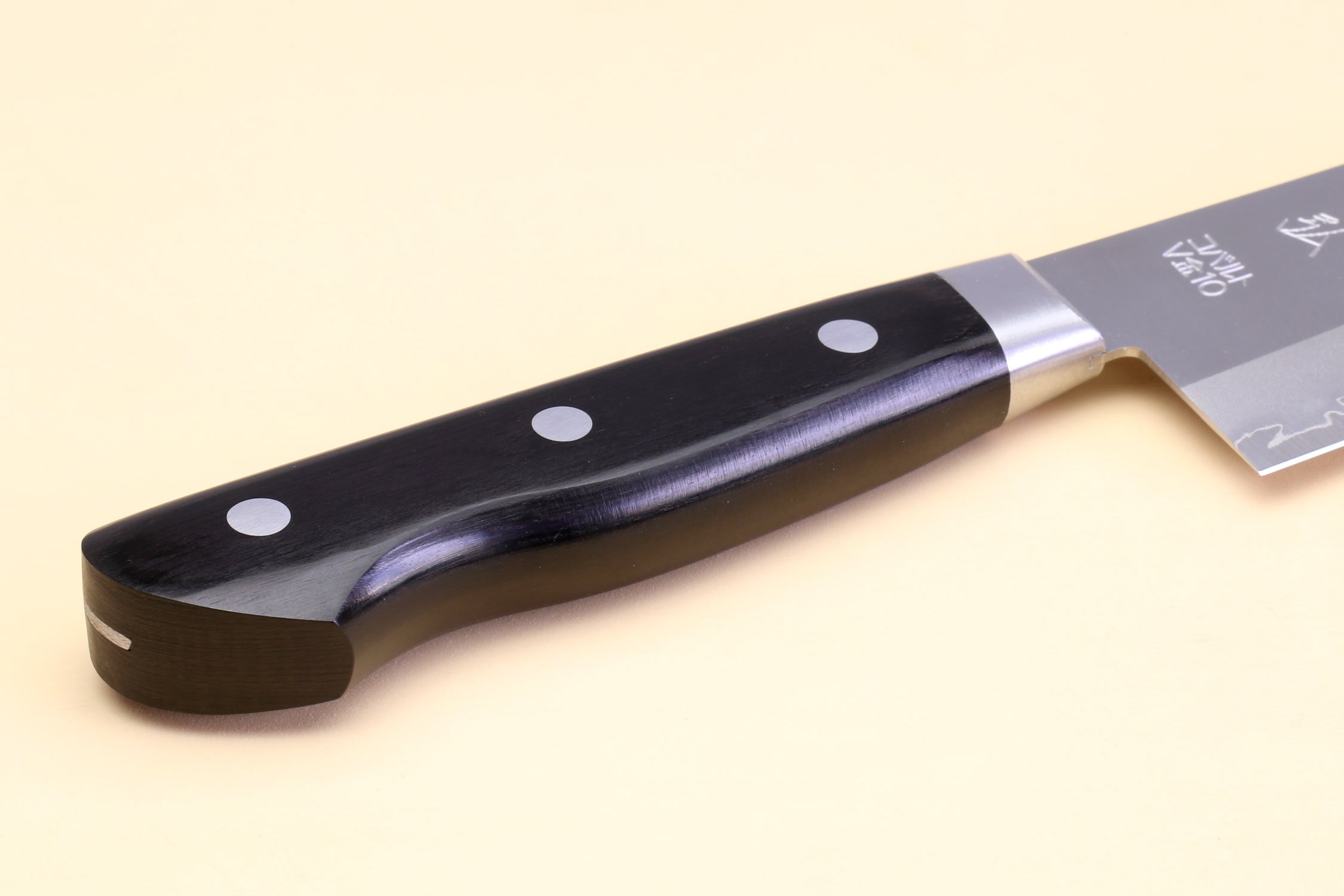 Gyuto chef knife handle close-up with black scales and three silver rivets.