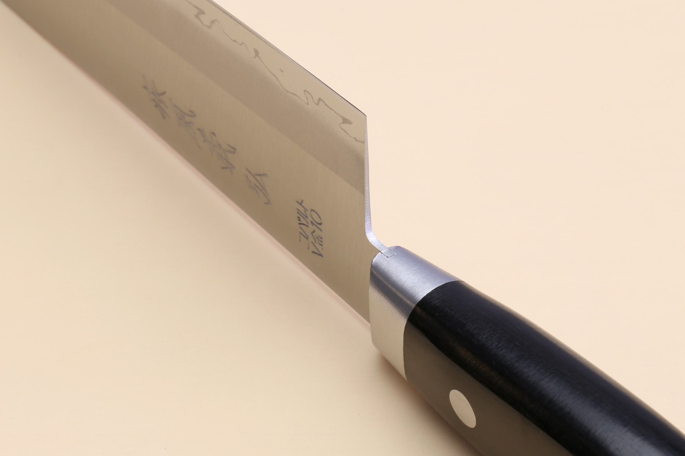 Gyuto chef knife close-up of spine and heel with black handle and rivet.