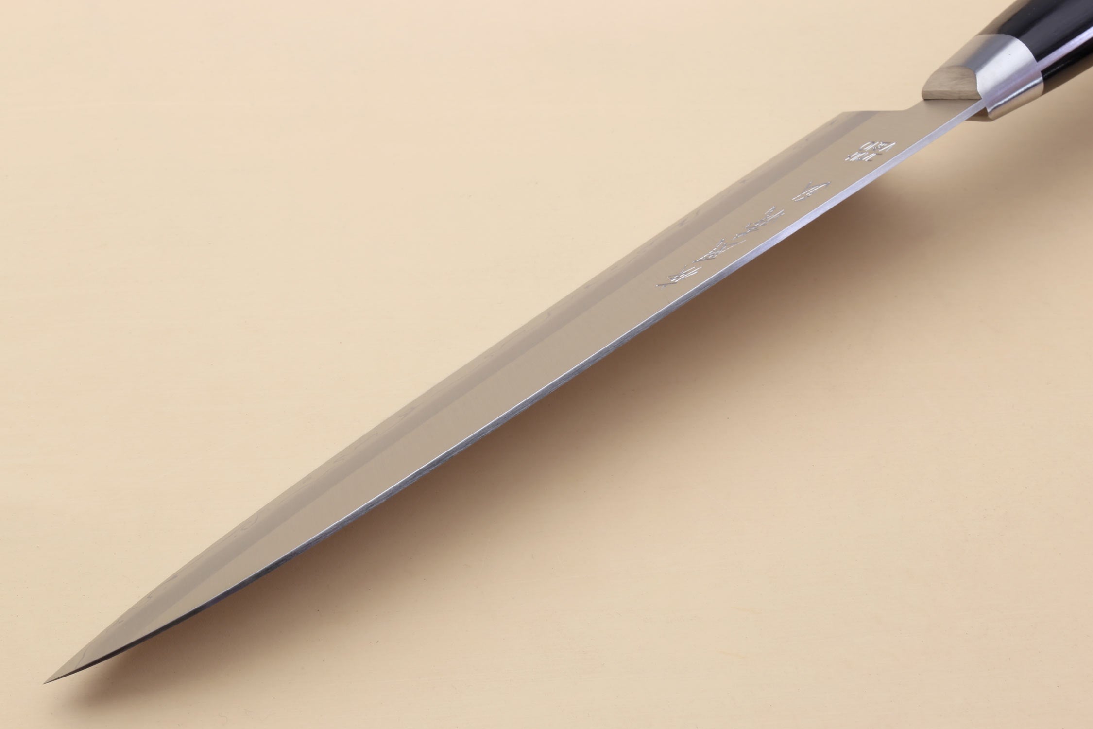 Gyuto chef knife with polished silver blade and black bolster, side profile.