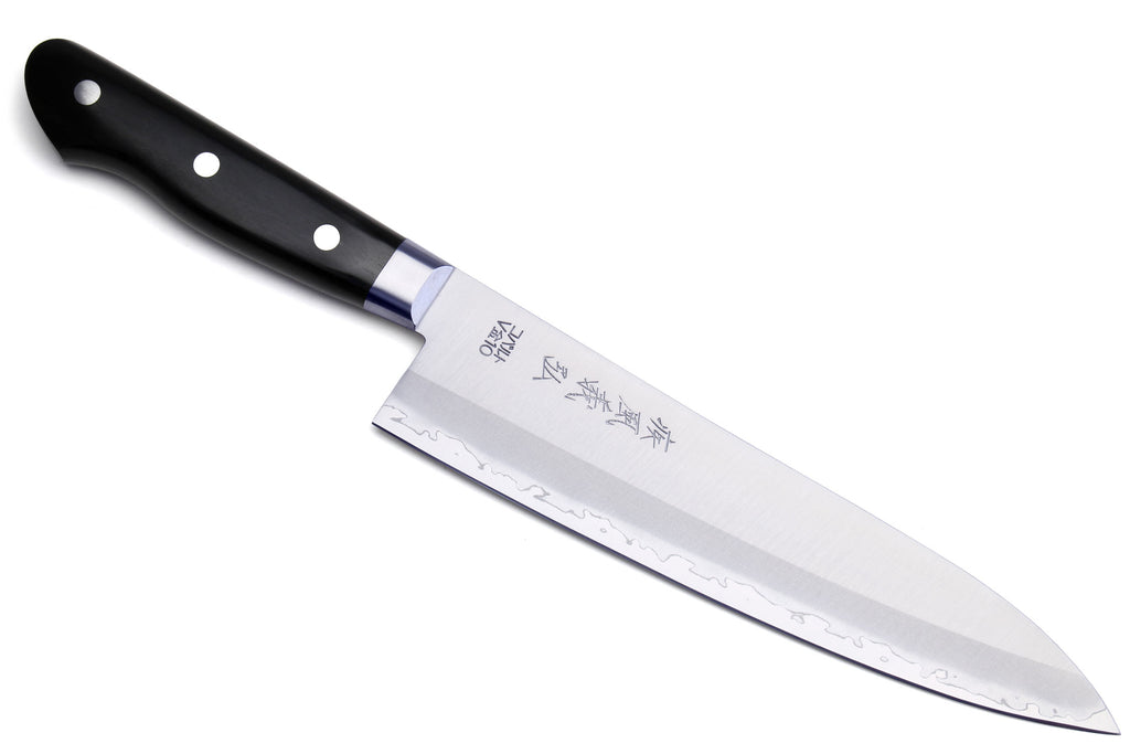 Gyuto chef knife with black handle and white steel blade, angled view.